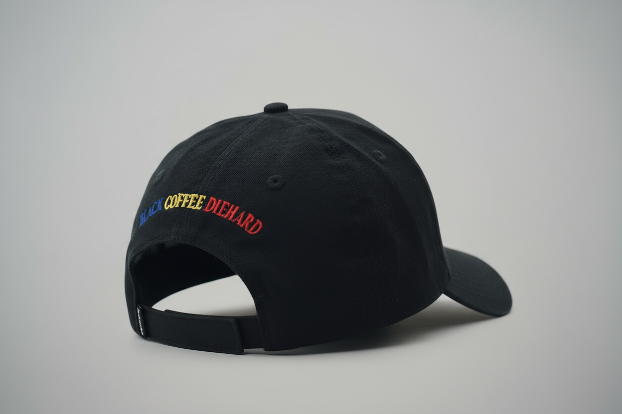 Black cap with 'BLACK COFFEE DIEHARD' text worn by a person, blurred background